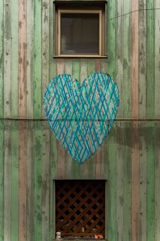 a painted heart on a weathered wall, small offerings tucked below