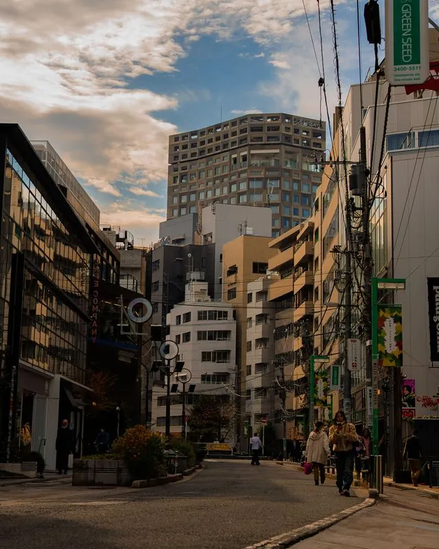 the street falls into shadow while the clouds catch the last light