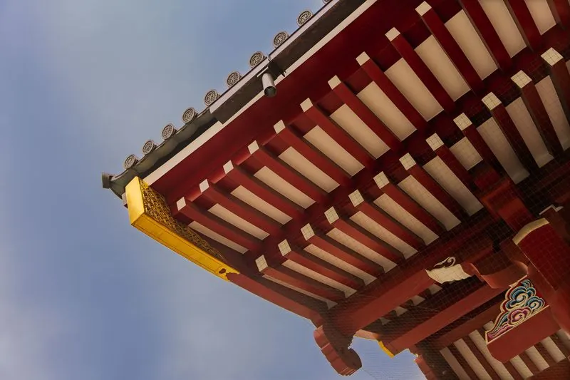 red rafters, a gilded corner, and a security camera watching from the tiles